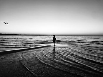 Silhouette woman standing on beach against sky