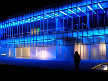 Low section of silhouette man standing in illuminated modern building