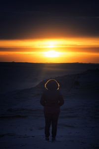 Silhouette man standing on beach against sky during sunset