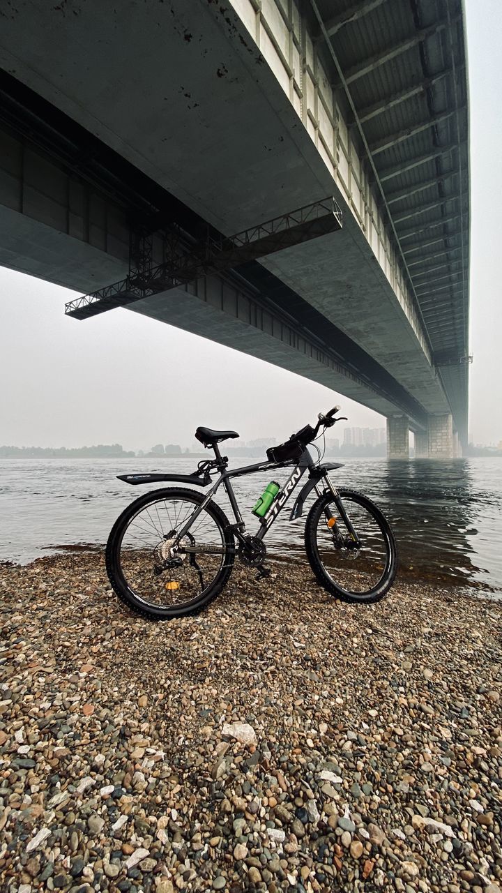 BICYCLES ON BRIDGE OVER RIVER AGAINST SKY