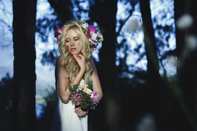 Woman wearing flowers while standing in forest