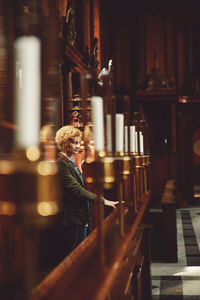 Thoughtful woman standing at pew in church