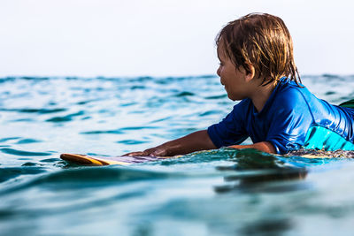 Side view of a 3 years old surfer on wooden surfboard