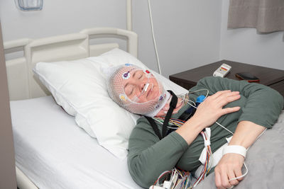 Middle aged woman measuring brain waves, examining polysomnography in sleep lab