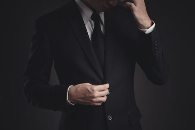 Midsection of a man holding camera over black background