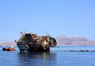 Shipwreck in sea against clear blue sky