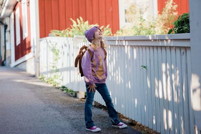 Girl stood dressed for school looking up at the sky looking happy