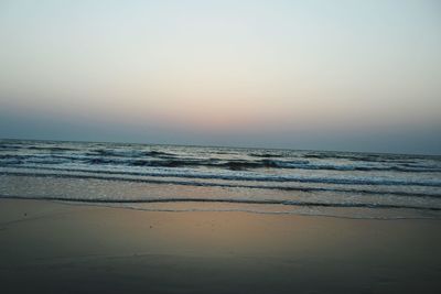 Scenic view of beach against clear sky during sunset