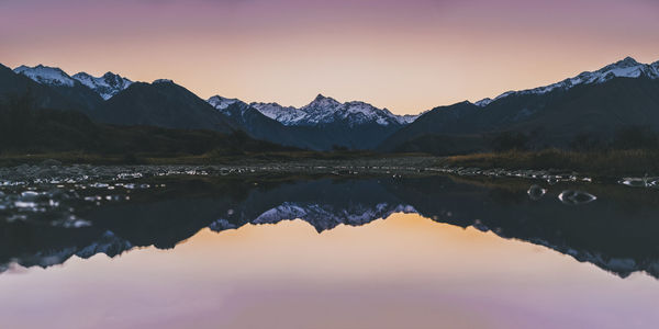 Scenic view of lake and mountains against sky during sunset