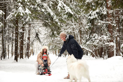 Portrait of woman with dog on snow covered field