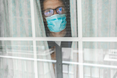 Middle-aged man in the medical mask is quarantined in the hospital and pressed her forehead against the window