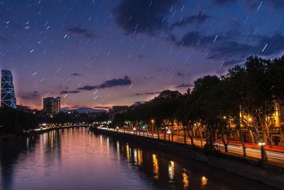 Illuminated bridge over river against sky at night