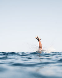 Man swimming in sea against clear sky