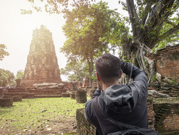 Rear view of senior man at temple against trees