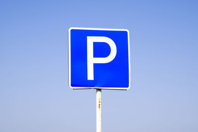 Close-up of road sign against clear blue sky