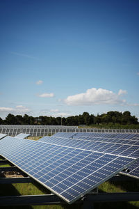 Solar panels on field against blue sky