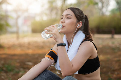 Young woman athlete takes a break, drinking water, out on a run on a hot day.