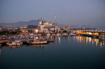 Sailboats in city by buildings against sky