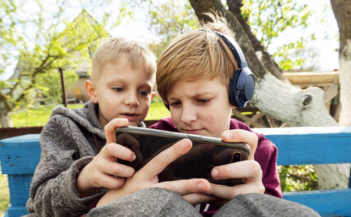 Close-up of cute kids playing games on mobile phone outdoors