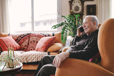 Portrait of smiling senior man telephoning with smartphone at home