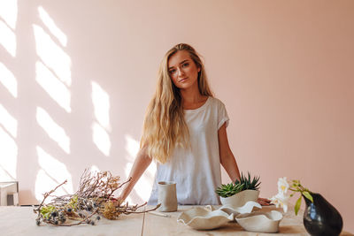 Portrait of beautiful woman on table against wall