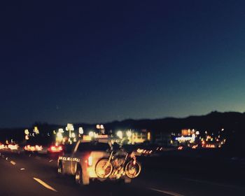 Illuminated cars against clear sky at night