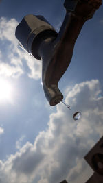 Low section of man holding umbrella against sky