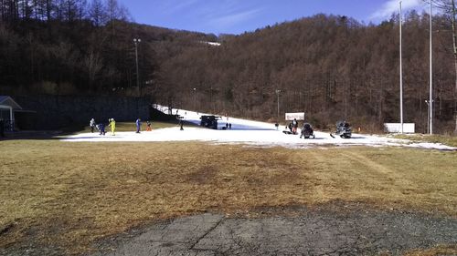 People on field by mountain against sky