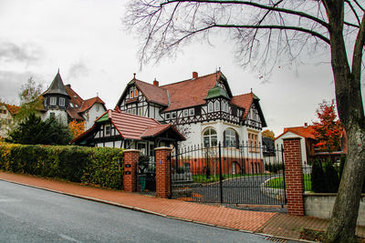 Houses and trees by road against sky