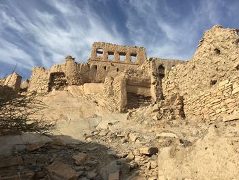 Low angle view of old ruin building against cloudy sky