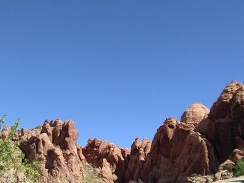 Low angle view of rock formations against clear blue sky