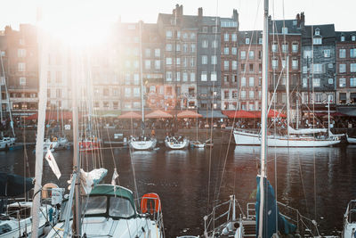 Sailboats moored on canal by buildings in city against sky