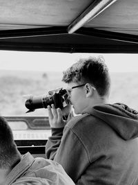 Teenager boy photographing while sitting in car