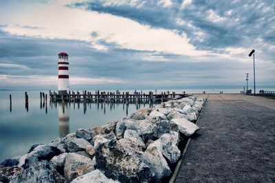 Lighthouse by sea against sky