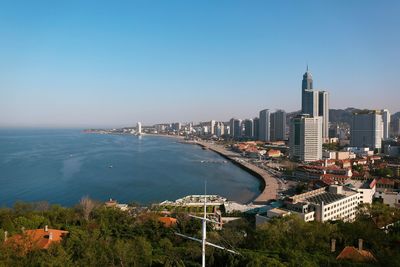 High angle view of cityscape by sea against clear sky