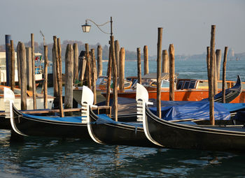Gondolas moored by wooden post at venetian lagoon
