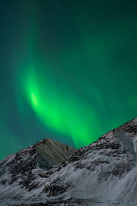 Low angle view of snowcapped mountain against sky at night