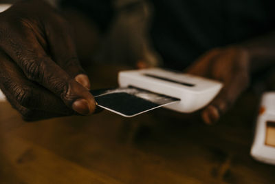 Close-up of cafe owner using credit card reader over kitchen counter at coffee shop