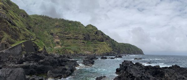 Panoramic view of rocks by sea against sky