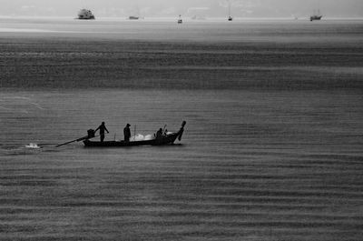 Silhouette people in sea against sky