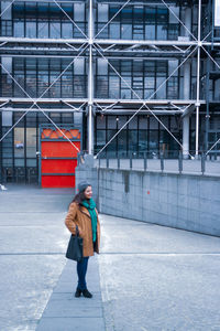 Full length side view of woman walking against pompidou centre  in paris