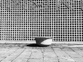 Container by patterned wall on sunny day