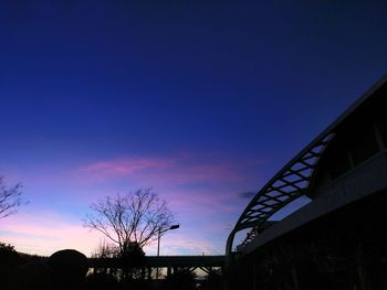 Low angle view of silhouette trees against blue sky