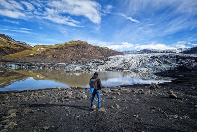 Rear view of man standing on mountain against sky