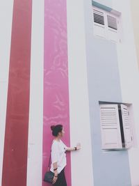 Side view of woman standing by building in city