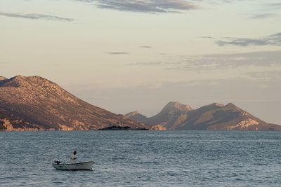 Man sailing on sea against mountains