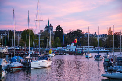 Sailboats moored at harbor against sky during sunset