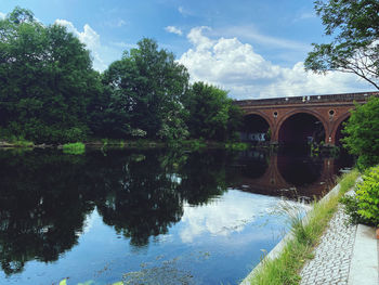 Arch bridge over river against sky