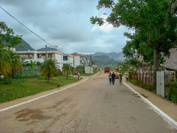 Rear view of people on road amidst buildings against sky