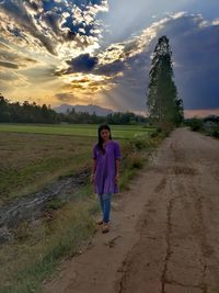 Full length of woman standing on field against sky